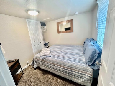 Carpeted bedroom featuring attic access and baseboards