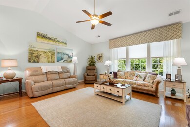 Living area with ceiling fan, vaulted ceiling, and wood finished floors