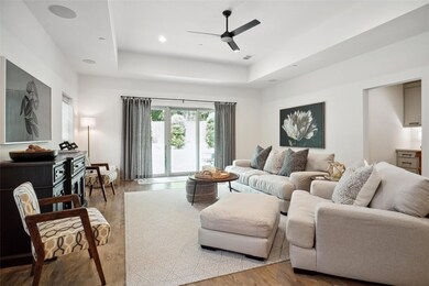 Living room featuring a tray ceiling, wood-type flooring, and ceiling fan