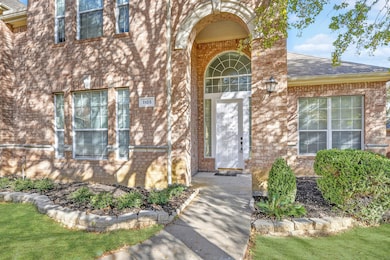 Doorway to property featuring brick siding, roof with shingles, and a lawn