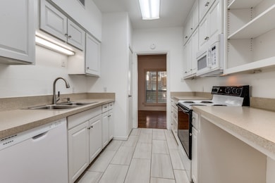 Kitchen featuring open shelves, white appliances, light countertops, and white cabinetry