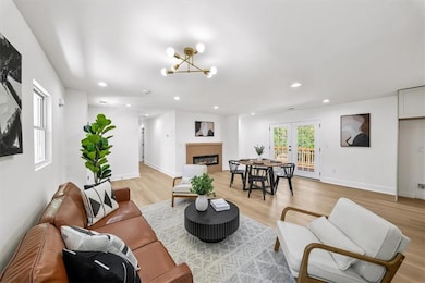 Living area with a glass covered fireplace, light wood-type flooring, recessed lighting, french doors, and a chandelier