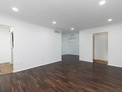 Empty room featuring ornamental molding, dark wood
