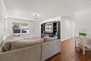 Living room with ornamental molding and wood finished floors