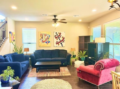 Living room with stairs, a ceiling fan, dark wood