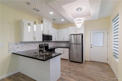 Kitchen with appliances with stainless steel finishes, a peninsula, dark countertops, tasteful backsplash, and white cabinets