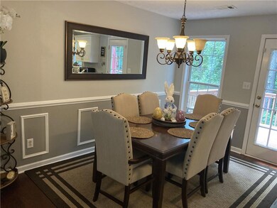 Kitchen with appliances with stainless steel finishes, under cabinet range hood, a chandelier, a sink, and dark wood finished floors