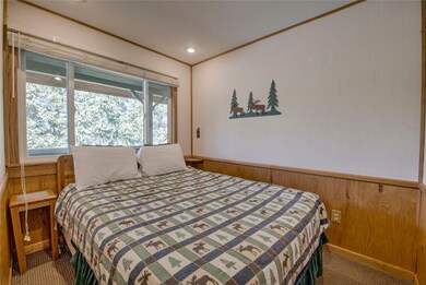 Carpeted bedroom featuring ornamental molding and wood walls