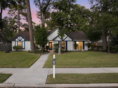 Beautiful brick exterior with striking blue trim is surrounded by sculpted trees and neatly manicured lawns, enhancing the property’s high curb appeal. A wide walkway leads to the inviting front entrance, with abundant green space highlighting the home’s warm and welcoming setting.