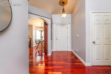 Foyer featuring a notable chandelier, baseboards, visible vents, arched walkways, and wood finished floors