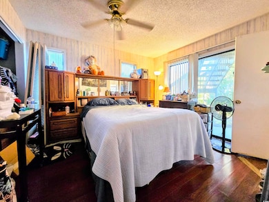 Bedroom with ceiling fan, wood walls, dark wood-ty