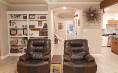 Sitting room with crown molding and light hardwood
