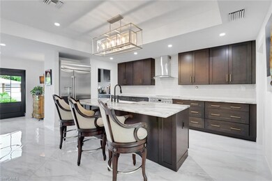 Kitchen with wall chimney range hood, tasteful backsplash, dark brown cabinets, light marble finish flooring, and pendant lighting