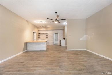 Unfurnished living room featuring wood finished floors, a ceiling fan, and track lighting