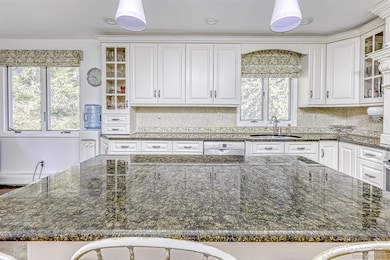 Kitchen with glass insert cabinets and dark stone countertops