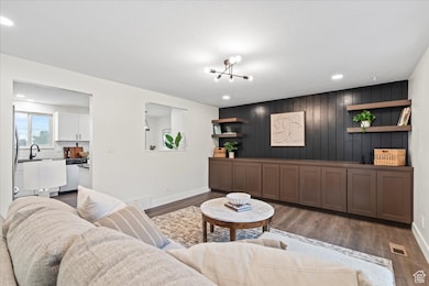 Living room with dark wood finished floors, recessed lighting, and wood walls