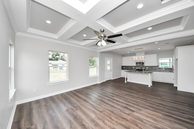 The open-concept living area seamlessly connects to the kitchen, offering an ideal layout for both everyday living and entertaining. Beautiful luxury vinyl plank flooring brings warmth and durability, while elegant crown molding and a striking tray ceiling elevate the space with timeless architectural detail - (representation photo).