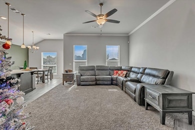 Living room with a chandelier, a ceiling fan, ornamental molding, light wood finished floors, and vaulted ceiling