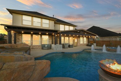 Another view of the extended covered patio, complete with gas connection for outdoor grill, ceiling fans, and string lighting.  In the foreground is the custom rock waterslide complete with grotto waterfall.