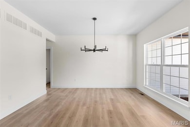 Unfurnished dining area with light hardwood / wood-style flooring and an inviting chandelier