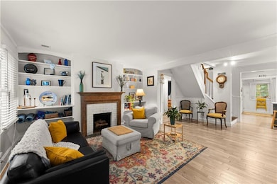 Living room with stairway, ornamental molding, light wood finished floors, and a fireplace
