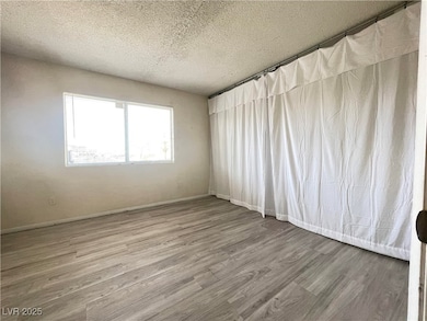 Unfurnished room with a textured ceiling and wood
