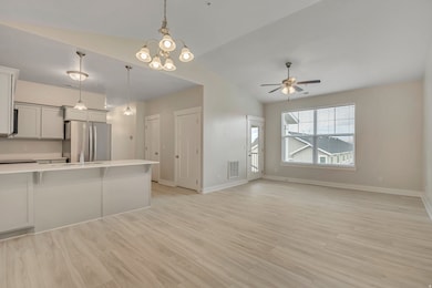 Unfurnished living room with vaulted ceiling, light wood finished floors, a chandelier, and ceiling fan
