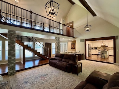 Living room with decorative columns, a chandelier, high vaulted ceiling, healthy amount of natural light, and beamed ceiling
