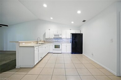 Kitchen with white appliances, lofted ceiling, a peninsula, decorative backsplash, and light countertops