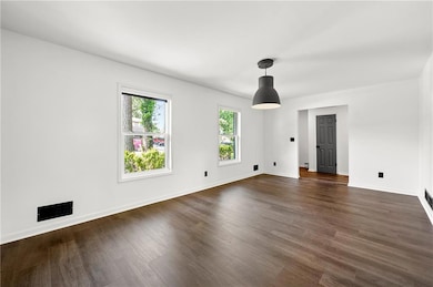 Unfurnished room featuring dark wood-style flooring, baseboards, and a baseboard heating unit