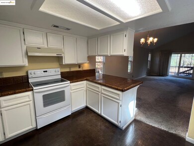 Kitchen with white range with electric stovetop, white cabinetry, dark carpet, a chandelier, and vaulted ceiling