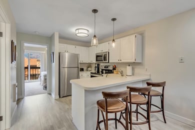 Kitchen featuring appliances with stainless steel finishes, light countertops, pendant lighting, white cabinets, and a peninsula