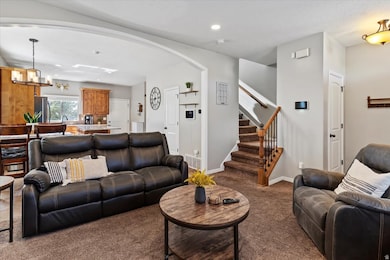 Carpeted living room with stairway, arched walkways, a chandelier, and recessed lighting