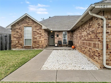 Entrance to property with a shingled roof and brick siding