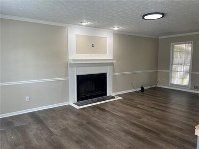 Unfurnished living room with a fireplace, wood finished floors, a textured ceiling, and crown molding