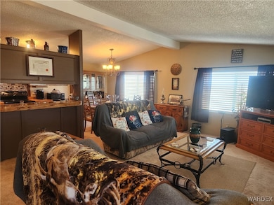 Carpeted living room with vaulted ceiling with bea