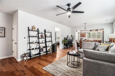 Living area featuring ceiling fan, dark wood-style floors, and baseboards