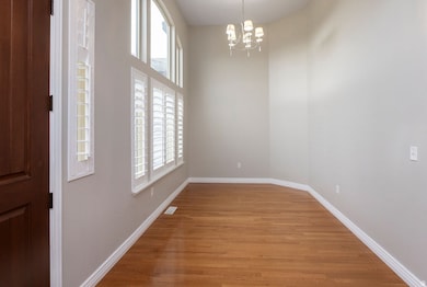 Empty room with light wood finished floors and a chandelier