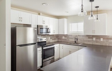 Kitchen featuring a sink, white cabinetry, applian