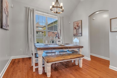 Dining area featuring lofted ceiling, light wood-type flooring, arched walkways, and a chandelier