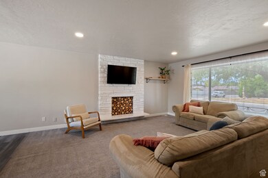 Living area featuring a textured ceiling, carpet floors, a fireplace, and recessed lighting