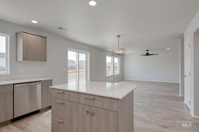 Kitchen featuring stainless steel dishwasher, light brown cabinetry, light countertops, light wood-type flooring, and modern cabinets