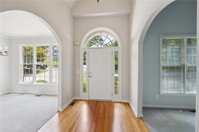 Foyer entrance with healthy amount of natural light, arched walkways, and light wood-type flooring