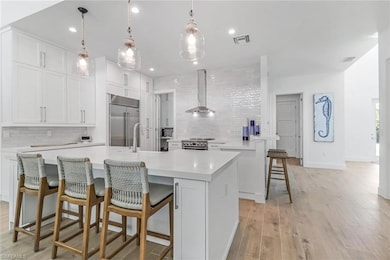 Kitchen with wall chimney range hood, appliances w