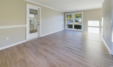 Unfurnished living room featuring a textured ceiling, LVP flooring and ornamental molding