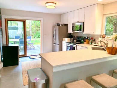 Kitchen featuring appliances with stainless steel finishes, backsplash, a kitchen breakfast bar, a peninsula, and white cabinetry