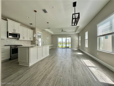 Kitchen with an island with sink, white cabinetry,