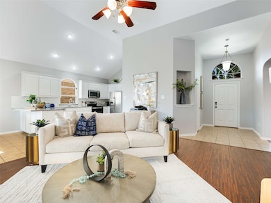 Living area with light tile patterned floors, a ceiling fan, high vaulted ceiling, arched walkways, and recessed lighting