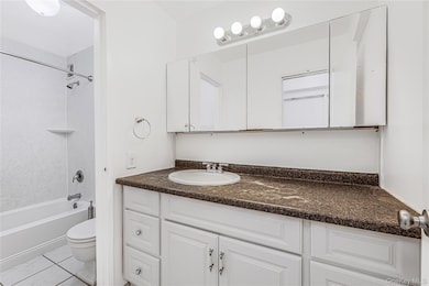 Bathroom with vanity, shower / bath combination, and light tile patterned flooring