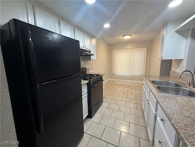 Kitchen featuring black appliances, extractor fan, white cabinetry, light tile patterned floors, and light countertops